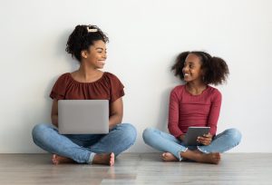 Happy black mom and teen kid using gadgets